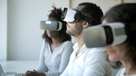Konzentrierte-Menschen-Mit-VR-Headsets-Sitzen-Im-Büro
